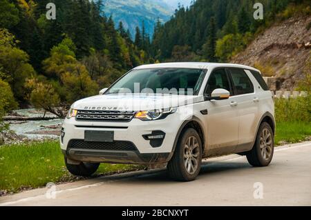 Land Rover Discovery Sport in Alpine Scenery on the raod with no name between Batang and the Ganbai Road, Sichuan Province, China. Stock Photo