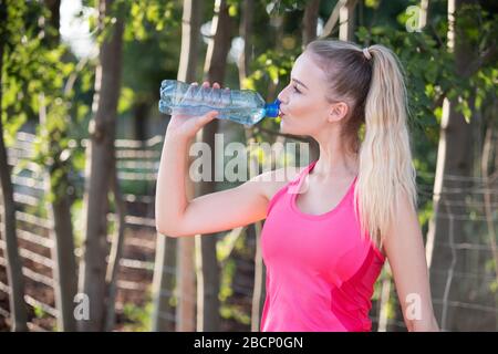 Woman takes a break from sports and drinks from her water bottle Stock Photo