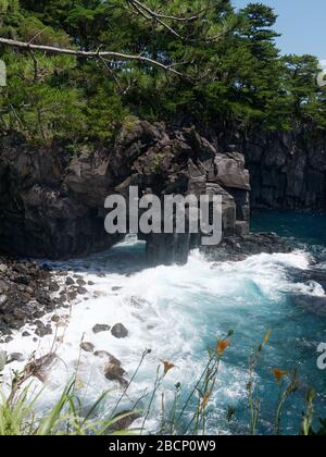 Wild rocky cliffs with columnar joints at the Jogasaki coast in Izu, Japan. Waves of the ocean crushing against the hexagonal rocks. Stock Photo