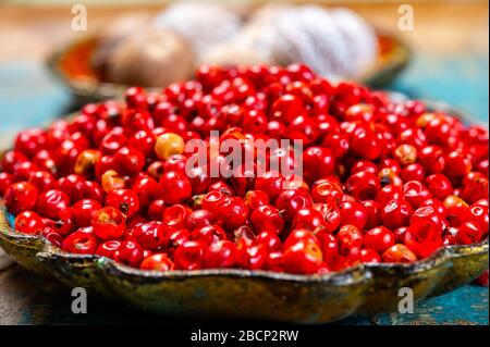 Bowl with dried red round peppers and nutmegs close up Stock Photo