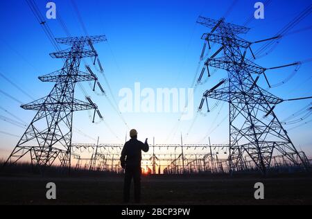 In the evening, electricity workers and pylon silhouette Stock Photo