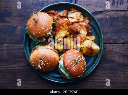 Three different mini burgers with beef and vegetables and chips in a plate American food Stock Photo