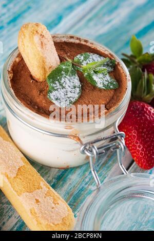 tiramisu in a glass Cup on a wooden table, next to mint and bagel Stock Photo