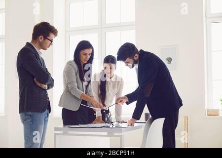 Businesspeople team in a meeting discussing a startup project at a table in an office with windows. Stock Photo