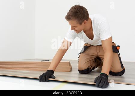 Carpenter worker installing laminate flooring in the room. Build a floating floor - flooring - laying laminate Stock Photo