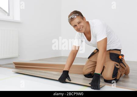 Carpenter worker installing laminate flooring in the room Stock Photo