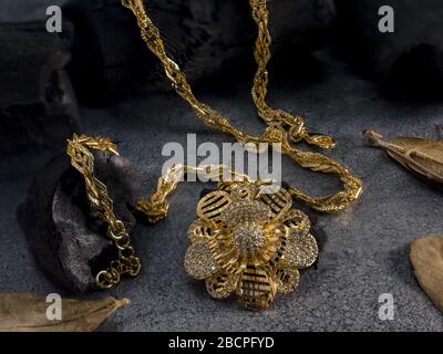gold necklace and earring on black coal background Stock Photo
