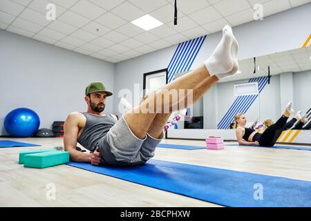 Real training of a group of people in a fitness center. Beautiful women and men do sport exercises in the gym. Stock Photo