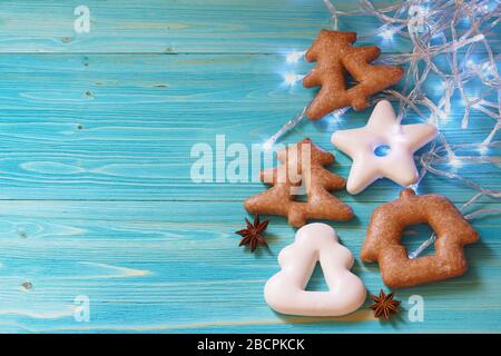 Gingerbread in the shape of a star, Christmas tree and house, star anise and garland on a blue wooden background Stock Photo