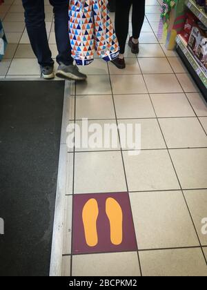 Social distancing guideline marks on a Sainsbury's supermarket floor, showing people where to stand, in the time of the Coronavirus COVID 19 pandemic crisis, in Glasgow, Scotland, April 2020. Stock Photo