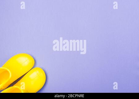 Pair of Yellow rubber boots stand on a blue violet background. Top view. Copy space. Free space. Stock Photo