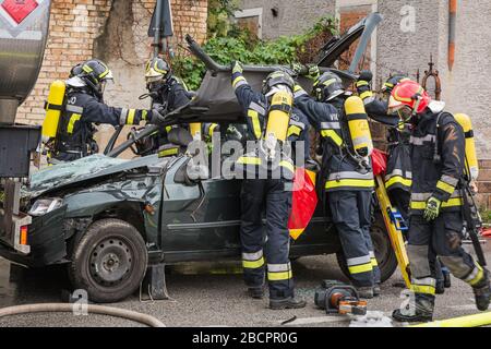 firefighters crewss rescue trapped driver during a road accident simulation with cars, train and trucks. firefighters with Breathing Apparatus and Hyd Stock Photo