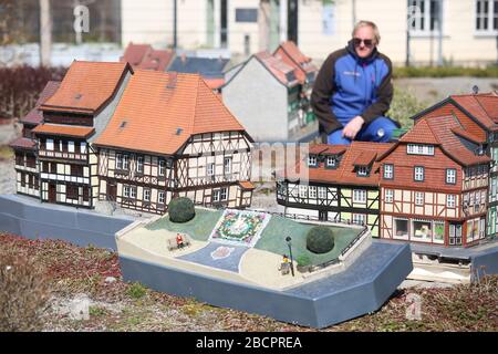 25 March 2020, Saxony-Anhalt, Wernigerode: An employee looks at models of half-timbered houses and the flower clock in Wernigerode in the Miniaturenpark Wernigerode. More than 60 models of famous Harz sights on a scale of 1:25 are shown in the Miniaturenpark. Due to the corona crisis the opening of the season will be postponed for an uncertain time. Photo: Matthias Bein/dpa-Zentralbild/ZB Stock Photo