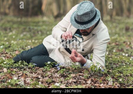 Man studying flower through magnifier Stock Photo