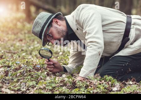 Man studying flower through loupe Stock Photo