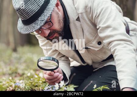 Man studying flower through magniglass Stock Photo