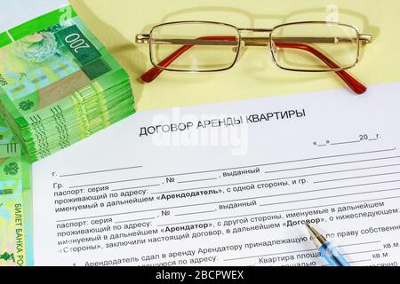 Registration of an apartment rental agreement. A form, pen, glasses, and Russian rubles on the table. The inscription in Russian 'apartment rental Agr Stock Photo