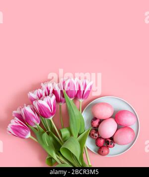 Easter pink table setting with eggs and a bouquet of spring flowers of tulips. Vertical orientation. Copy space, top view, flat lay. Stock Photo