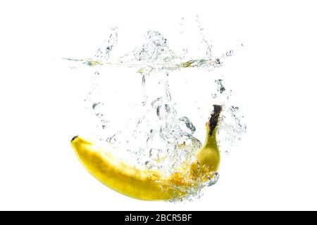 one banana falling into water on a white background with splashes. Stock Photo