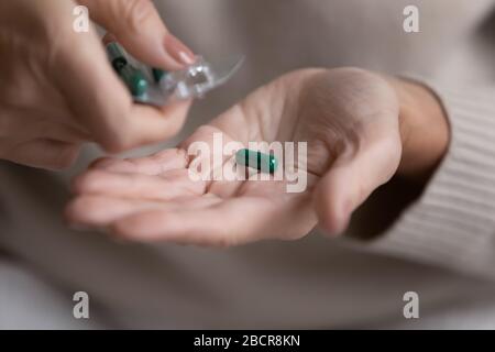 Middle aged woman pouring capsules pills out of plastic blister. Stock Photo