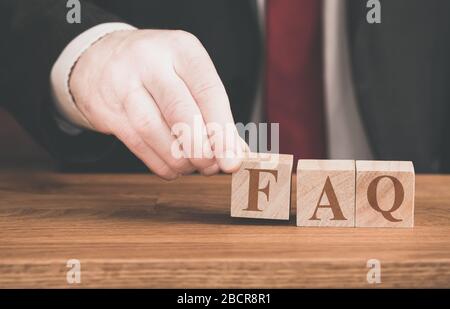 A concept background of a male spelling out the phrase FAQ or frequently asked questions for online website help pages and internet assistance Stock Photo