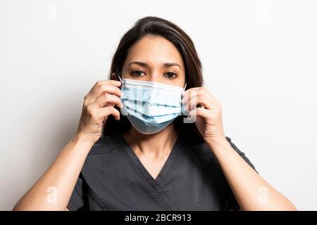 Young doctor putting on her mask. White background Stock Photo