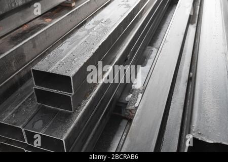 Stack of rolled metal products, gray steel pipes with rectangular cross-section, close-up photo with selective soft focus Stock Photo