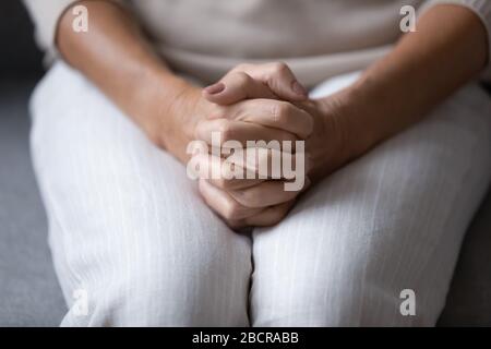 Close up wrinkled female hands clasped together on lap. Stock Photo