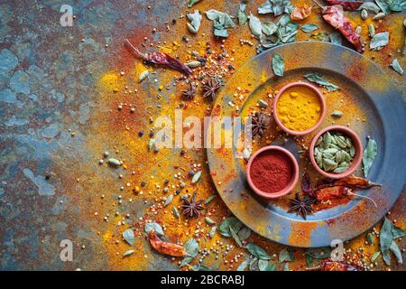 Aromatic spices on and around a pewter plate on slate background Stock Photo