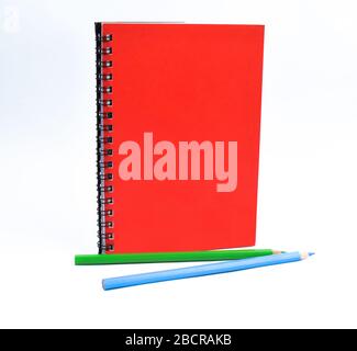Green and light blue colored wood pencil crayon placed in front of a red note paper book diary Stock Photo