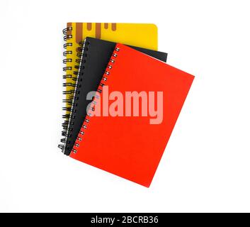 Three paper note diary of red black and yellow color placed on top of each other on a white background Stock Photo