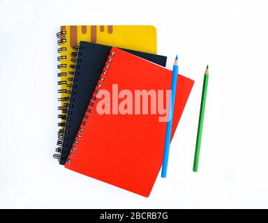 Two different colored wood pencil crayon placed with three different color notebooks on a white background Stock Photo