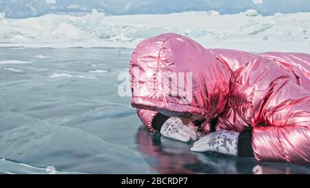 Girl walking on cracked ice of a frozen lake Baikal. Woman trave Stock Photo