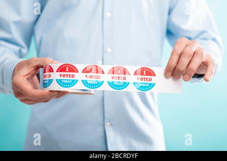 Man holding stickers with text i voted today on blue Stock Photo