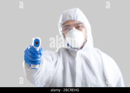 Infrared thermometer in hands of asian male disinfector Stock Photo