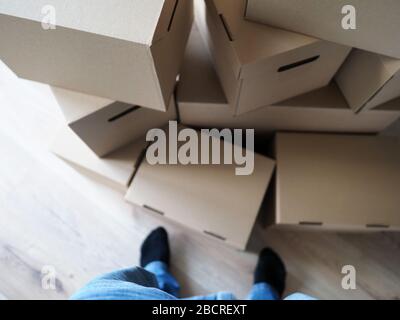 Male legs standing near huge pile of cardboard boxes Stock Photo