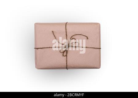 The box is wrapped in brown paper and tied with thread. Rectangular packaging isolated on a white background. Concept of mail delivery or event gift Stock Photo