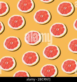 Pink ripe grapefruit slices on the orange background pattern Stock Photo