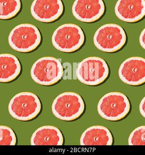 Pink ripe grapefruit slices on the green background pattern Stock Photo