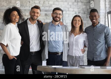 Portrait of standing in row smiling multiracial team embracing. Stock Photo