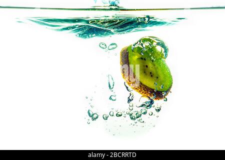 whole kiwi and sliced slices falling under water Stock Photo