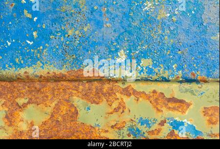 An old metal case with bright orange spots of rust through several layers of paint.Peeling paint on old rusty metal. Stock Photo