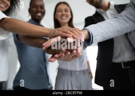 Close up happy diverse business people putting hands together. Stock Photo