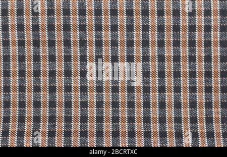 Background with a checkered pattern.Dark checkered fabric in black and brown color of a blanket, trousers or shirt. Stock Photo