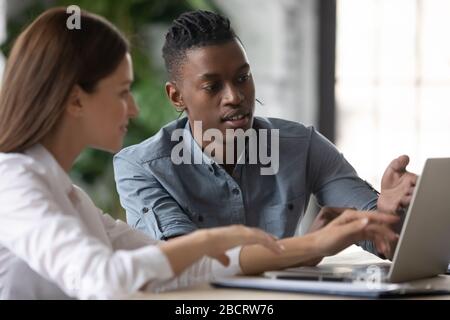 Confident african american businessman talking with businesswoman using laptop. Stock Photo