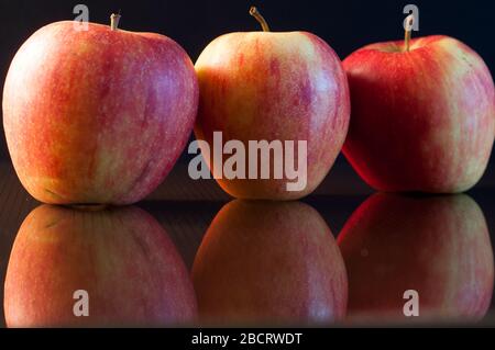 close-up of three red apples on dark glass. black background. Stock Photo