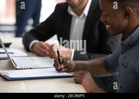 Close up happy african american businessman signing partnership agreement. Stock Photo