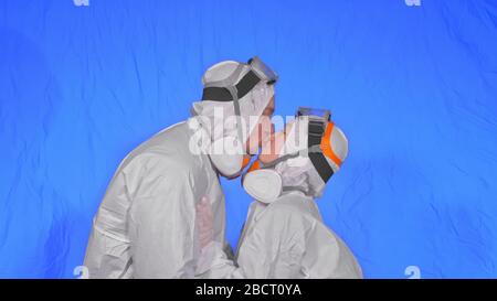 Doctor man and woman in protective costume suit, gas protect medical spray paint mask. Love couple kiss and hug, health worker in respirator Covid-19. Stock Photo
