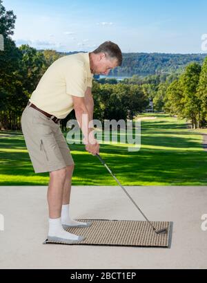 Senior caucasian man practicing his golf grip and swing on a mat in bedroom at home and imagining he was outside on a real golf course Stock Photo