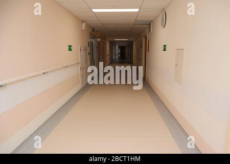 Empty long corridor or hall of a modern hospital. Beige walls and floor. Exit to the stairs and glass doors. Stock Photo